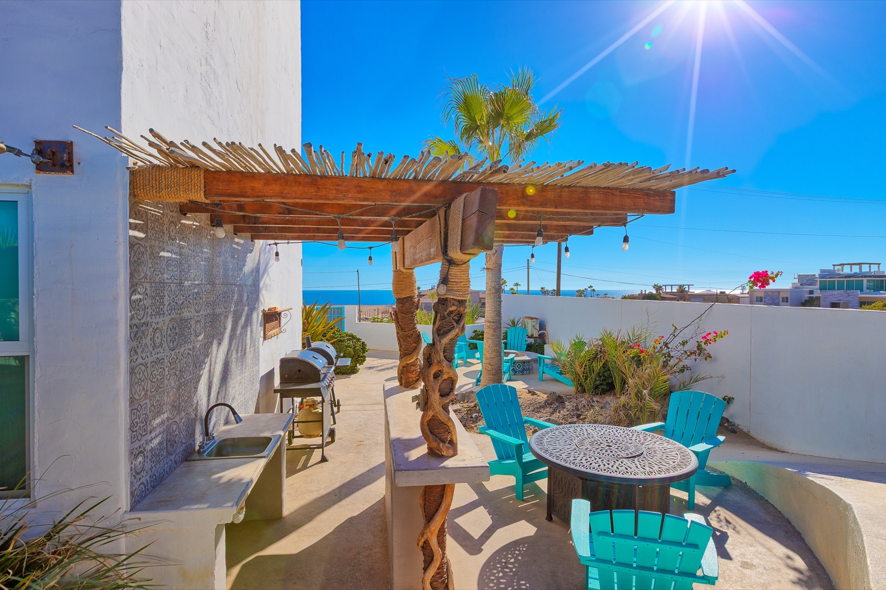 Casa Gio outdoor dining area with turquoise chairs and an ocean view