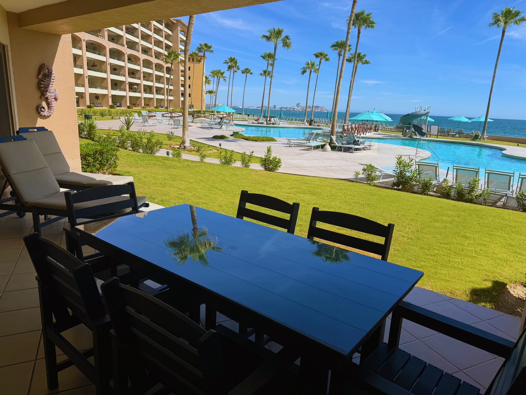 Updated patio dining and lounge furniture overlooking the resort pool and sea